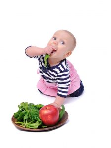 Baby eating healthy foods - fresh vegetables and fruits.