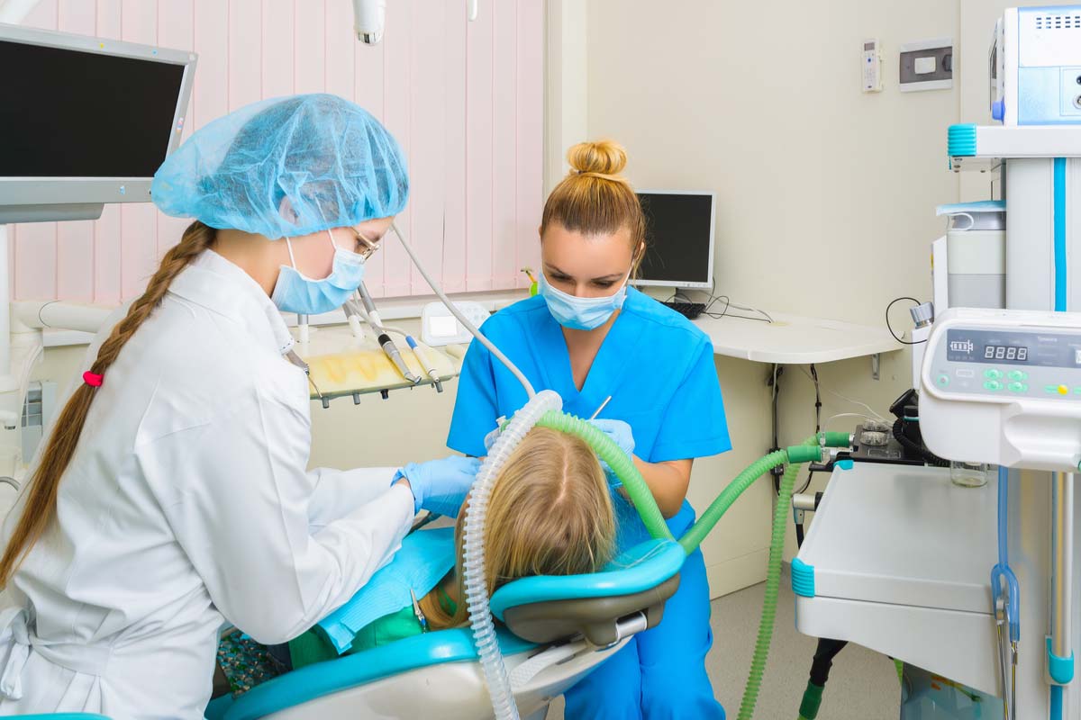 Dentist and her hygienist working with a sedated patient.